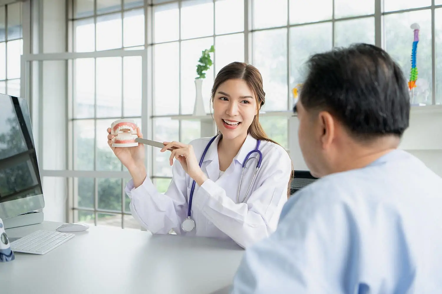 During a Free Orthodontic Consultation at Smile City Orthodontics in Sunnyvale TX, a female doctor shows a dental model to a seated male patient in a bright office.