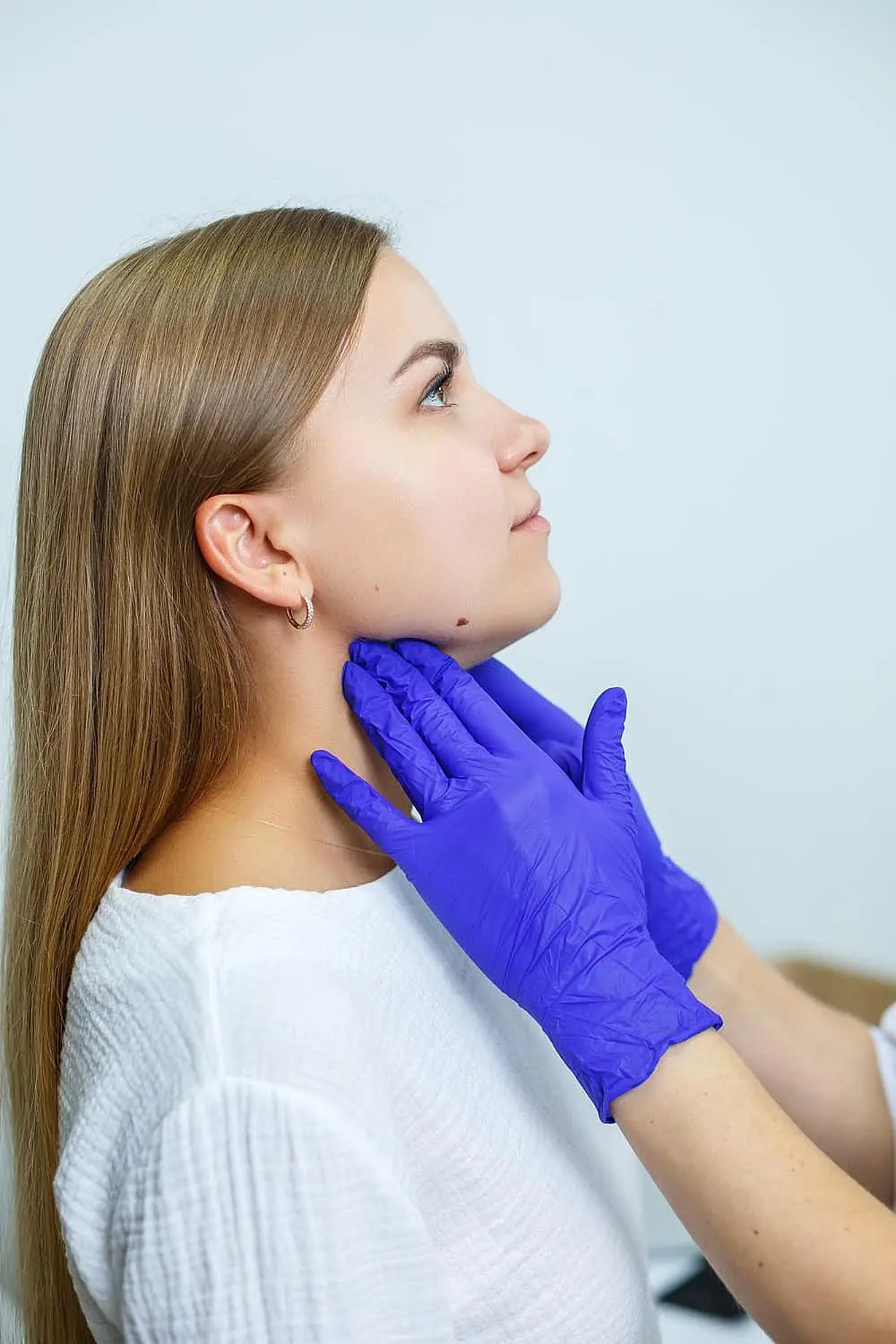At Smile City Orthodontics in Sunnyvale TX, a gloved professional examines a seated woman’s neck and jawline from the side, likely evaluating her for jaw surgery.