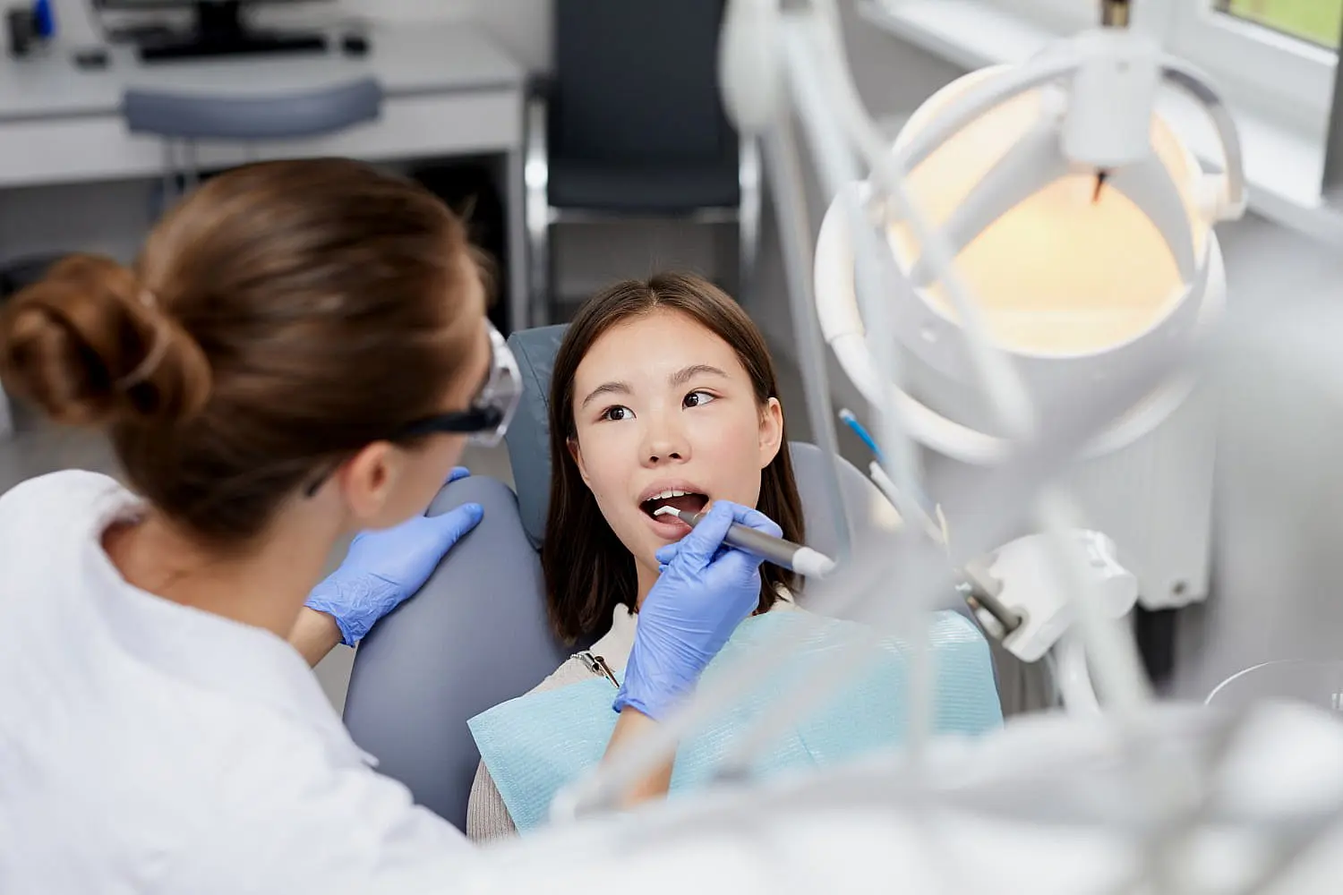 At Smile City Orthodontics in Sunnyvale TX, a dentist wearing gloves uses dental tools to examine a mouth breather's teeth in a brightly lit clinic.