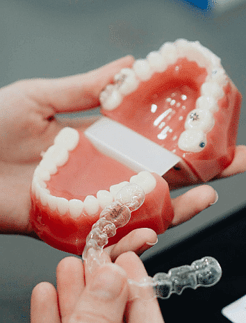At Smile City Orthodontics in Sunnyvale TX, a person demonstrates an Invisalign payment plan by fitting a clear aligner onto a dental model’s lower teeth, showing how straighter smiles are more accessible.