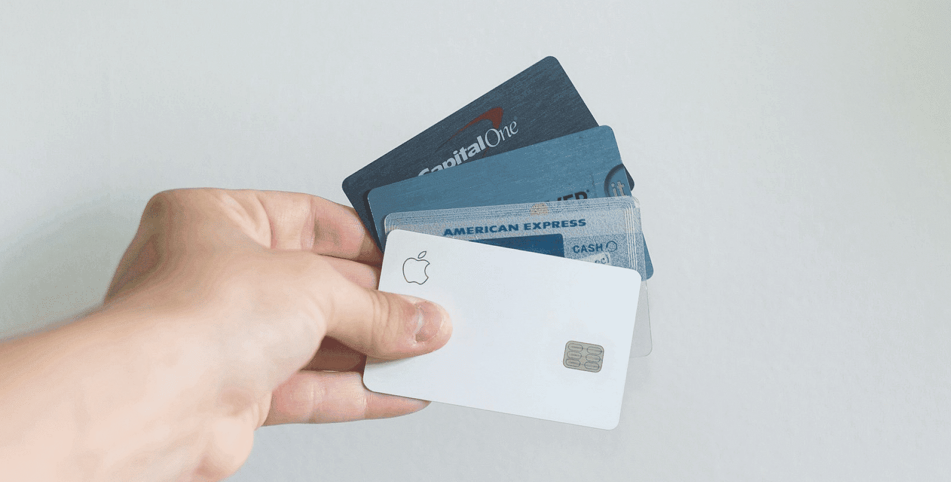 A hand fans out four credit cards—including Apple, American Express, and Capital One—against a plain background, perfect for managing an Invisalign payment plan at Smile City Orthodontics in Sunnyvale, TX.