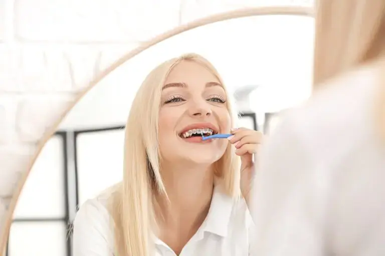 young woman metal braces toothbrush home - How to Floss with Braces in Sunnyvale, TX young woman metal braces toothbrush home - How to Floss with Braces in Sunnyvale, TX