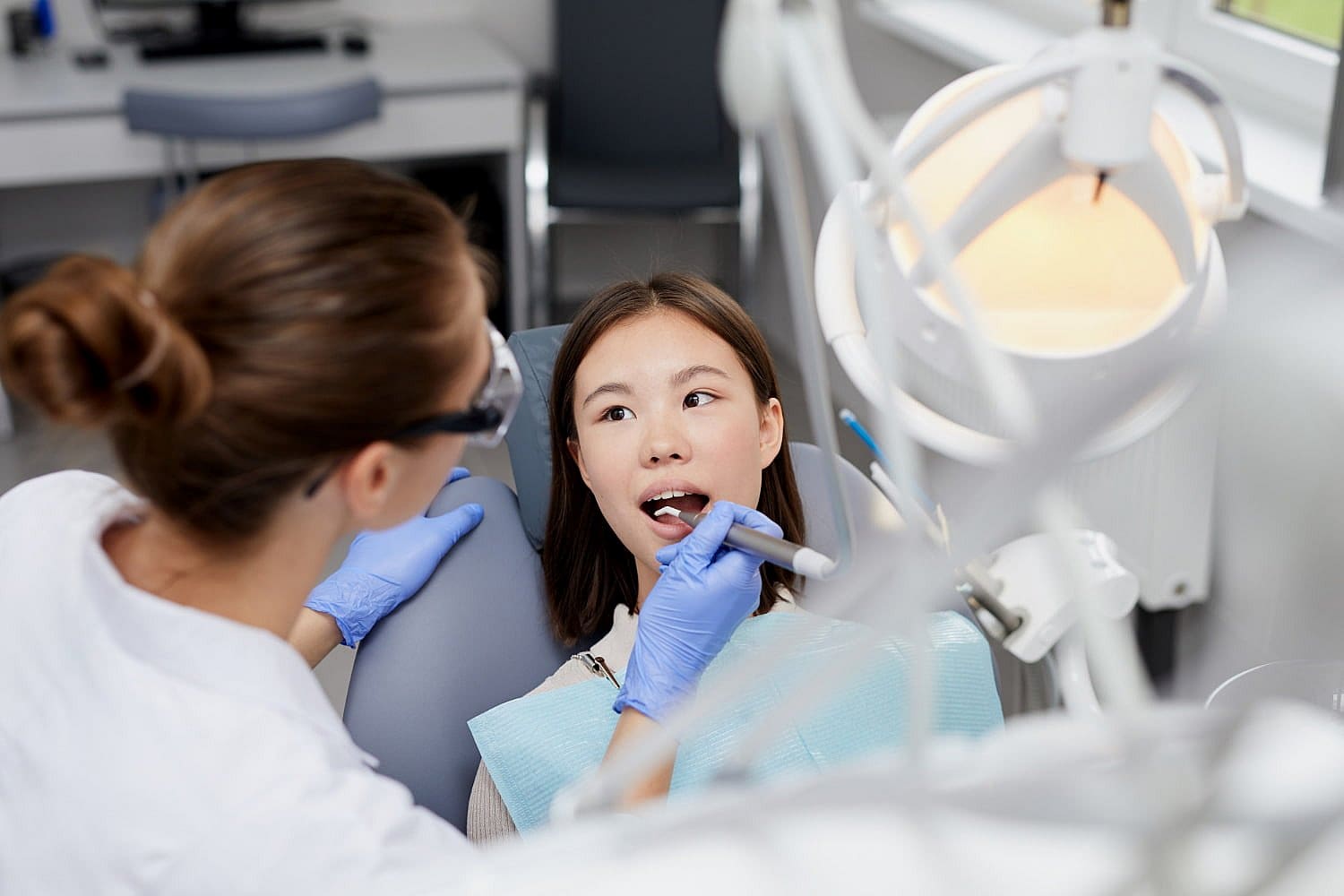 At Smile City Orthodontics in Sunnyvale TX, a dentist wearing gloves uses dental tools to examine a mouth breather's teeth in a brightly lit clinic.