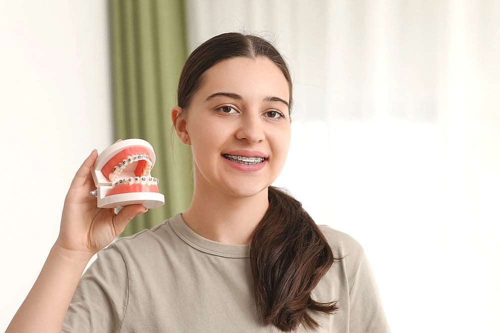 At Smile City Orthodontics in Sunnyvale TX, a young person with braces displays a dental model, highlighting adult orthodontic options.
