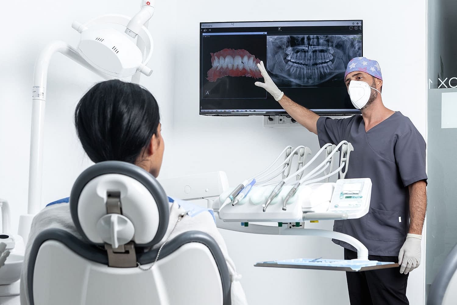 At Smile City Orthodontics in Sunnyvale TX, a dentist wearing a mask reviews dental X-rays on a screen and discusses possible jaw surgery options with a patient seated in the dental chair.