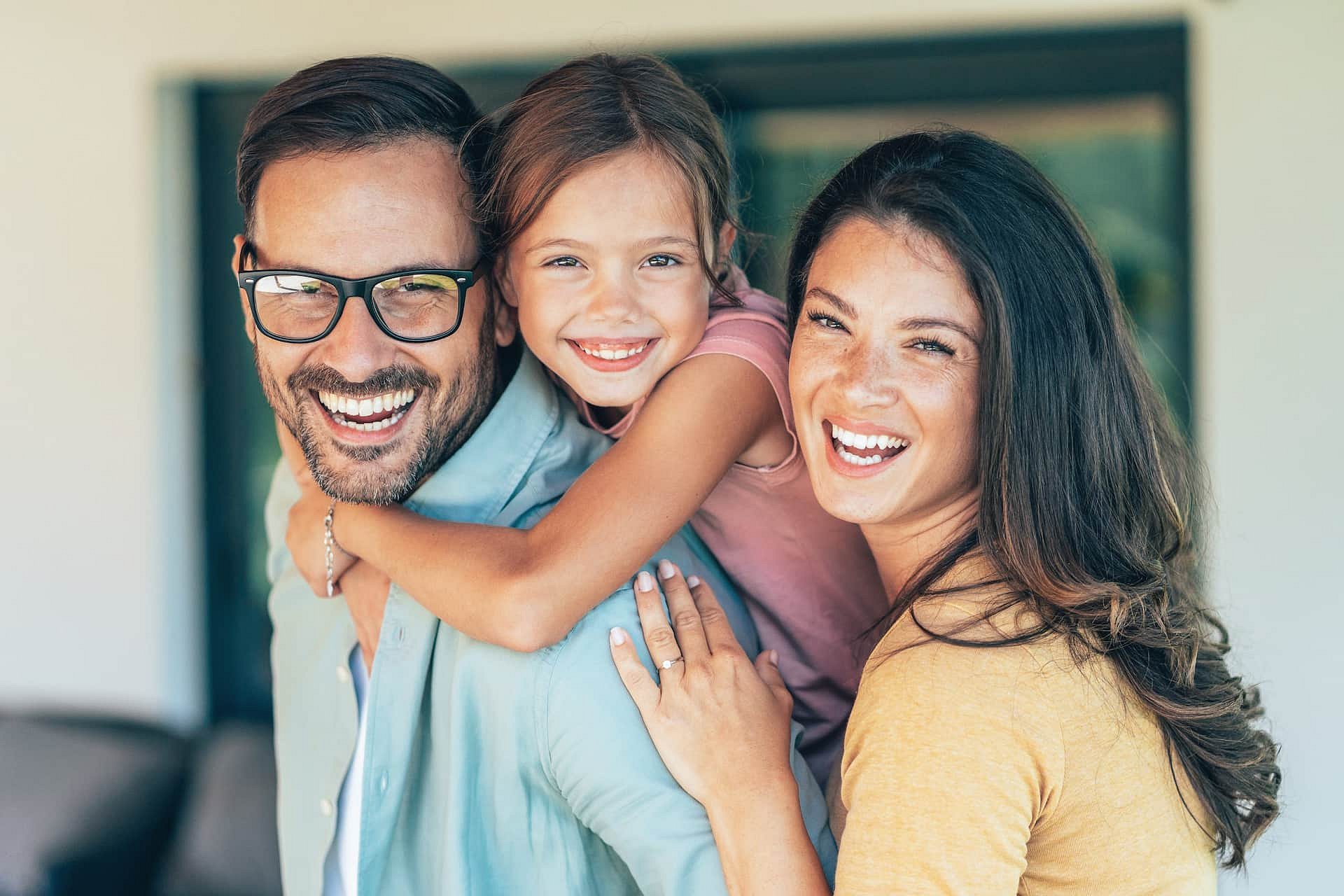 A smiling family embraces for the camera, reflecting why so many ask if Invisalign is covered by insurance at Smile City Orthodontics in Sunnyvale, TX.