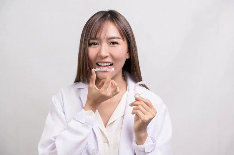 Young woman smiling and holding Invisalign aligner – can Invisalign fix overbite in Sunnyvale, TX.