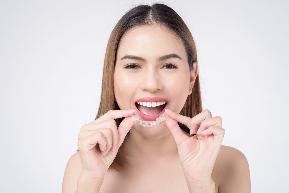 Confident woman demonstrating Invisalign aligner – can Invisalign fix overbite in Sunnyvale, TX.