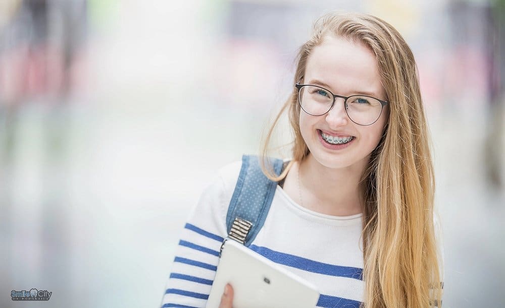 portrait of a smiling beautiful teenage girl with metal braces watermark - how long do braces take in Sunnyvale, TX. 