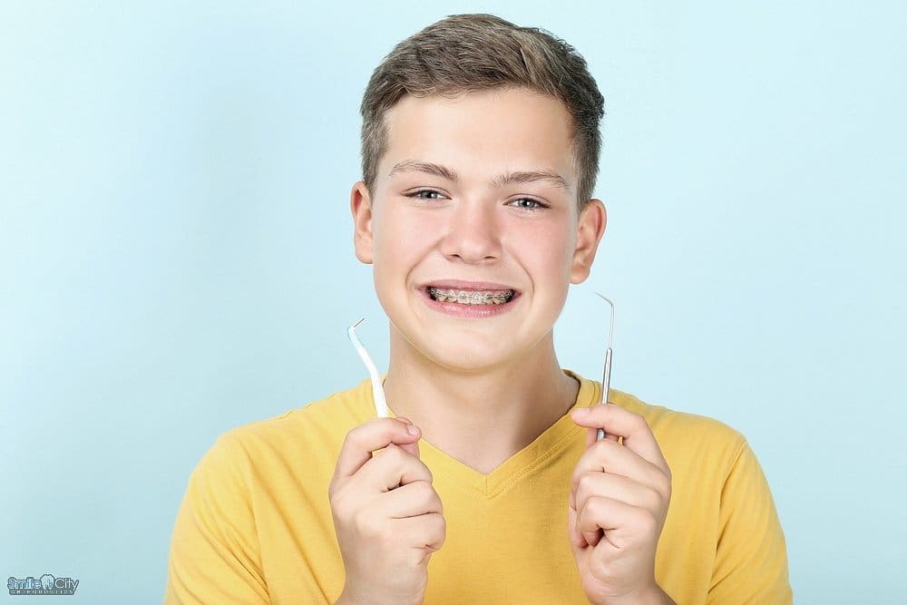 young man with metal braces toothbrush dentist tool - How to Floss with Braces in Sunnyvale, TX